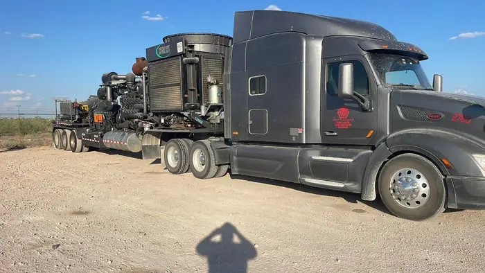 Two GTM Transport flatbed trucks parked nose to nose in the yard