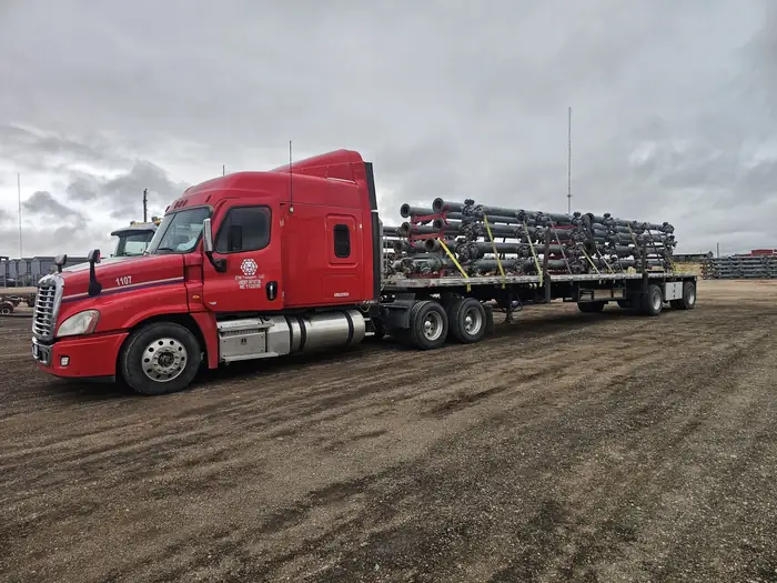 GTM Transport white Peterbilt flatbed hauling large diameter steel pipe