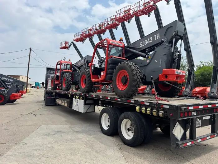 GTM Transport flatbed hauling telehandler forklifts for a job site