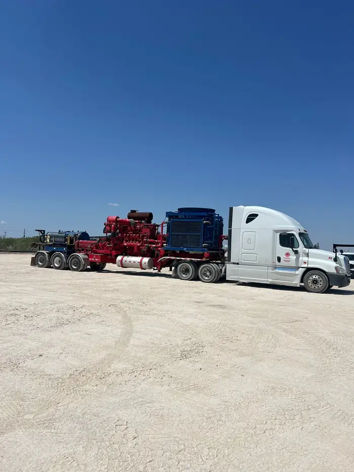 Crane loading palletized frac equipment onto a GTM Transport flatbed trailer