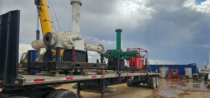 Crane setting heavy wellhead components onto a GTM Transport flatbed trailer